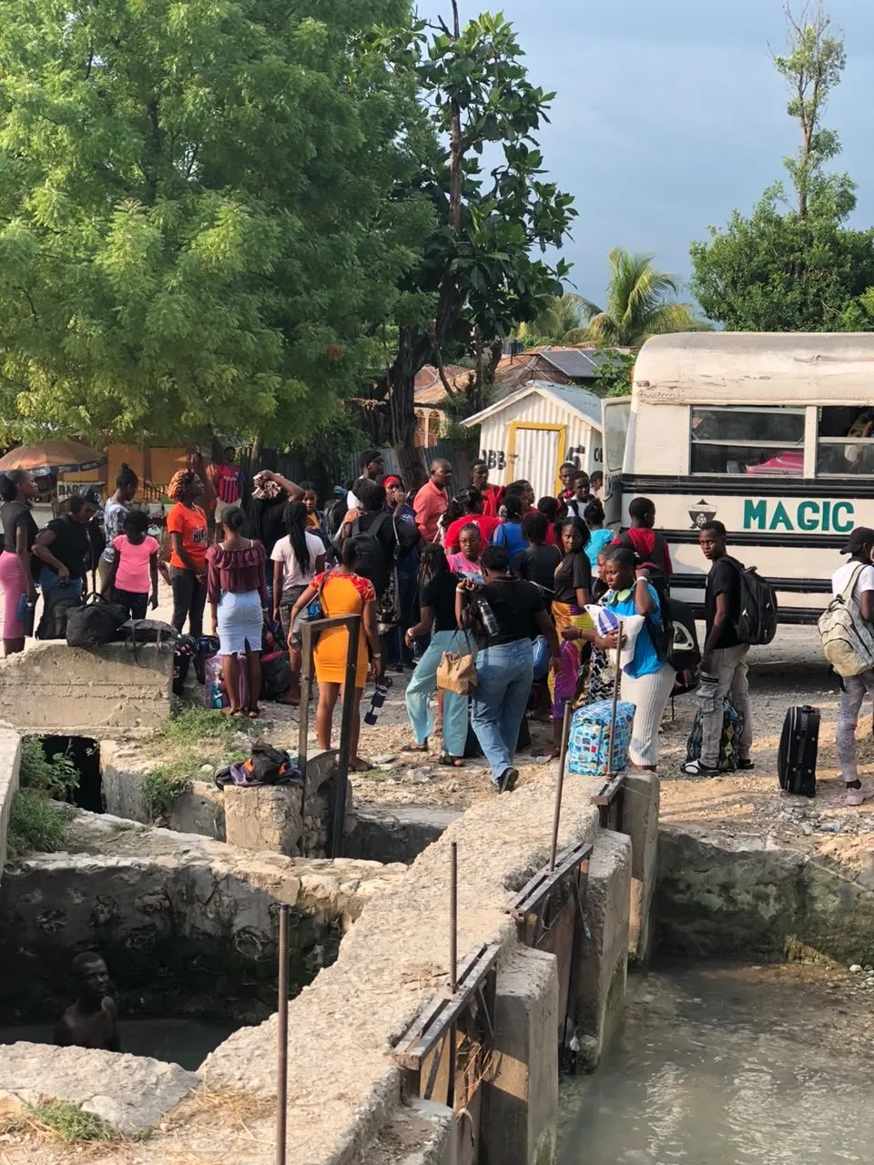 Campers with their bags gathering beside a bus on arrival day