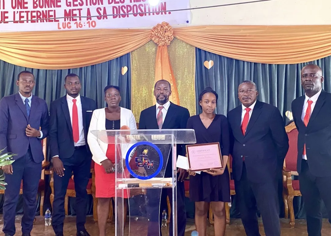 Church and ministry leaders standing with a student holding her certificate at a recognition ceremony
