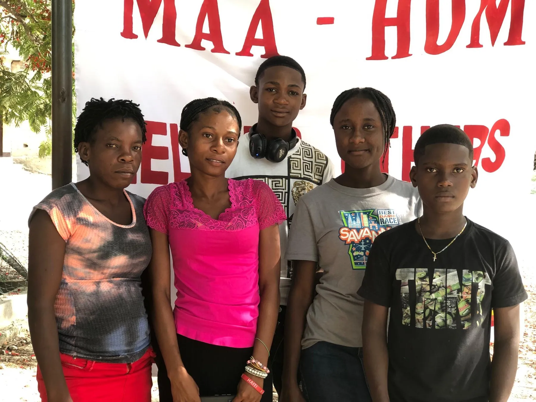 A group of young people and adults standing together in front of a ministry banner